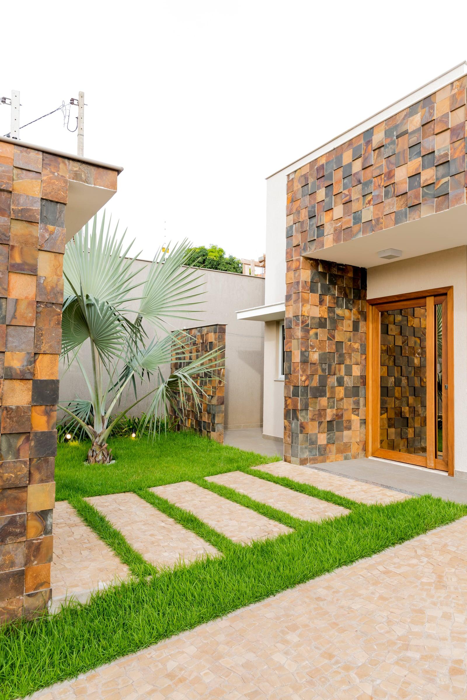 Casa Jacarandá em Rolândia, casa térrea com cobertura inclinada e parede contínua de tijolo aparente